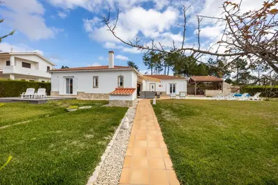 a white house with a grassy yard with a pathway at Casa dos Sonhadores in Aljezur