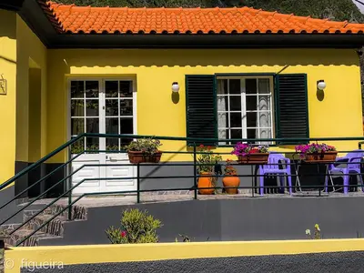 a yellow house with a balcony with tables and chairs at Terra Chã Cottage,FEEL Home, in São Vicente