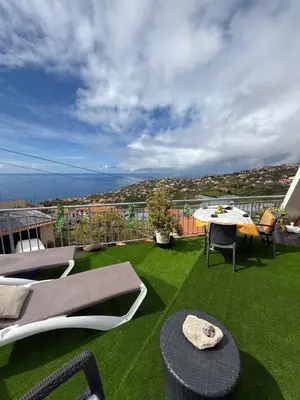 a patio with green grass and a table and chairs at Studio privado com vista mar e montanha in Ponta do Sol