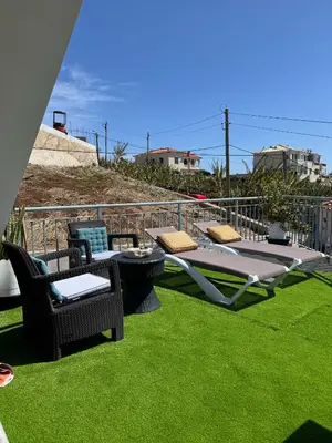 a patio with green grass and chairs on a balcony at Studio privado com vista mar e montanha in Ponta do Sol