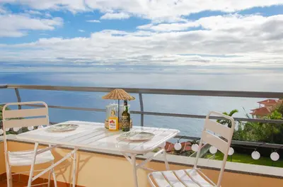 a table and chairs on a balcony with the ocean at Unique Tropical Style Penthouse with a Dreamy View - by Portugal Collection in Calheta