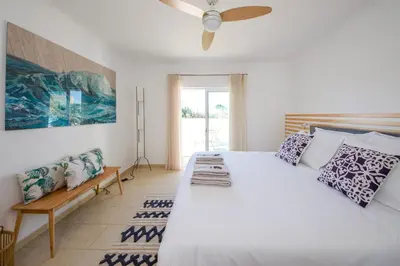 a bedroom with a large white bed with a fan at Casa da costa in Carrapateira