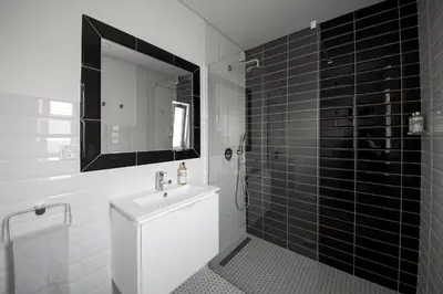 a black and white bathroom with a sink and a mirror at Casa da costa in Carrapateira