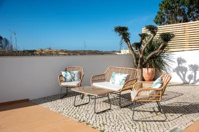 three rattan chairs and a table on a patio at Casa da costa in Carrapateira