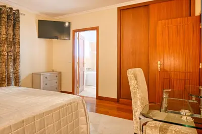 a bedroom with a bed and a desk and a television at Villa Mendonça, a Home in Madeira in Canhas