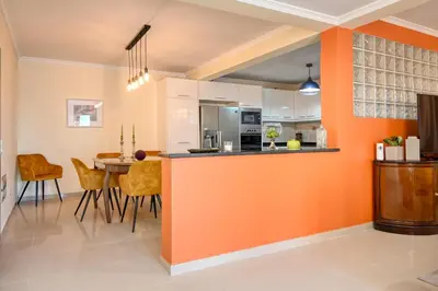 an orange kitchen with a table and chairs at Villa Mendonça, a Home in Madeira in Canhas
