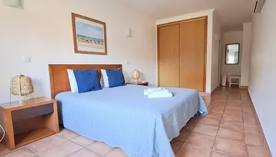 a bedroom with a large bed with blue pillows at Spacious Apartment near Porto de Mos Beach, Lagos. in Lagos
