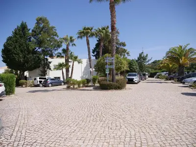 a cobblestone street with parked cars and palm trees at Spacious Apartment near Porto de Mos Beach, Lagos. in Lagos