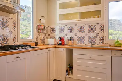 a kitchen with white cabinets and blue and white tiles at Villa Santa Madalena, a Home in Madeira in Arco da Calheta