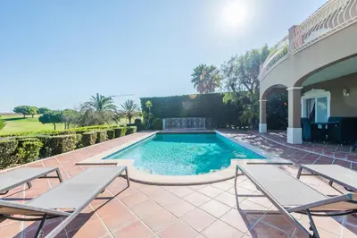 a swimming pool with chairs and a house at Boavista Golf and Spa Resort - 101 in Lagos