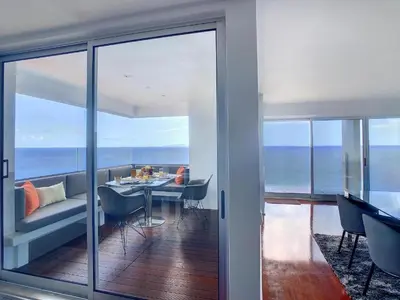 a dining room with a table and a view of the ocean at Luxurious Penthouse Suites direct on sea in Caniço