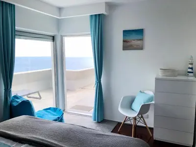 a bedroom with a bed with blue pillows and a window at Luxurious Penthouse Suites direct on sea in Caniço