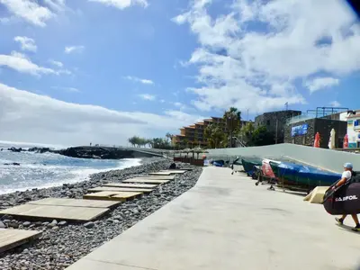a rocky beach with an umbrella and the ocean at Luxurious Penthouse Suites direct on sea in Caniço