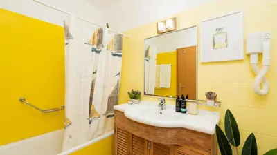 a yellow bathroom with a sink and a shower at The Seaview Studio by LovelyStay in Caniço