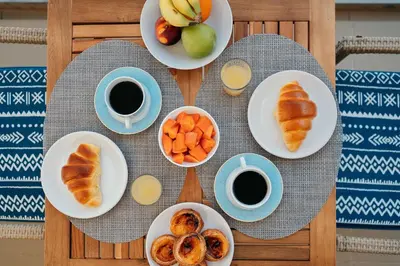 a table with plates of food and cups of coffee at Infinity pool & Amazing Sunset Ocean View in Funchal
