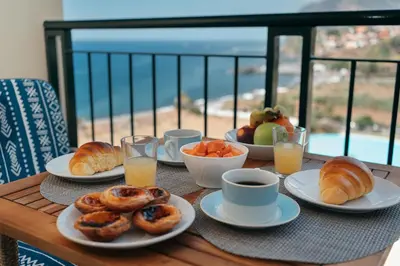 a table with plates of pastries and cups of orange juice at Infinity pool & Amazing Sunset Ocean View in Funchal