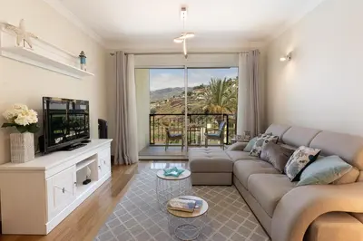 a living room with a couch and a television at Infinity pool & Amazing Sunset Ocean View in Funchal