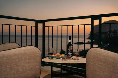 a table with a bottle of wine and glasses on a balcony at Infinity pool & Amazing Sunset Ocean View in Funchal