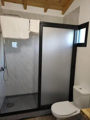 a bathroom with a toilet and a glass shower door at Ponta do Sol Private Apartment Sea View in Ponta do Sol
