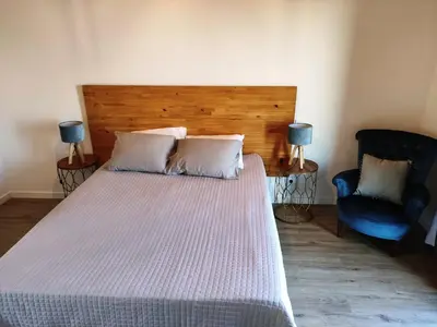 a bedroom with a large bed and a blue chair at Ponta do Sol Private Apartment Sea View in Ponta do Sol