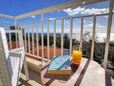 a glass of orange juice sitting on a table on a balcony at Lido Life Apartment by LovelyStay in Funchal