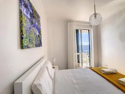a white bedroom with a bed and a large window at Lido Life Apartment by LovelyStay in Funchal