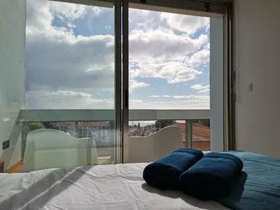 a bed with two blue pillows in front of a window at D Apartment - your home with breathtaking Views in Funchal