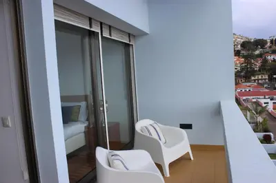 a balcony with two white chairs and a bed at D Apartment - your home with breathtaking Views in Funchal