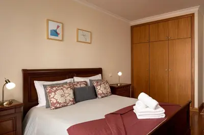 a bedroom with a bed and a wooden cabinet at Margarida's Apartment com piscina e vista mar in Funchal