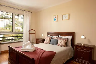 a bedroom with a large bed and a window at Margarida's Apartment com piscina e vista mar in Funchal