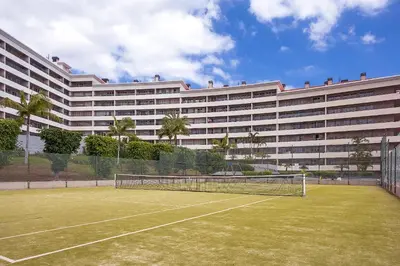 a tennis court in front of a large building at Margarida's Apartment com piscina e vista mar in Funchal