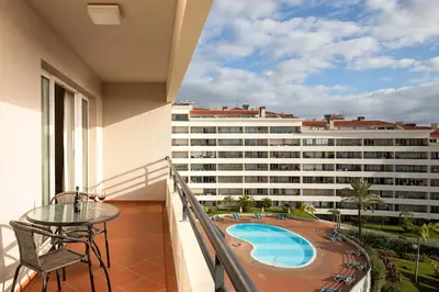 a balcony with a table and a view of a building at Margarida's Apartment com piscina e vista mar in Funchal