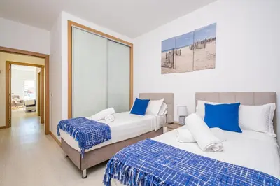 a bedroom with two beds with blue and white sheets at Blue Paradise Apartment in Caniço