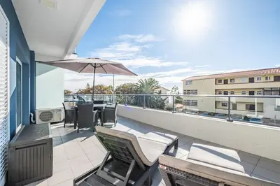 a patio with chairs and an umbrella on a balcony at Blue Paradise Apartment in Caniço