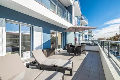 a balcony with chairs and an umbrella at Blue Paradise Apartment in Caniço