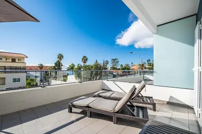a patio with two lounge chairs on a balcony at Blue Paradise Apartment in Caniço