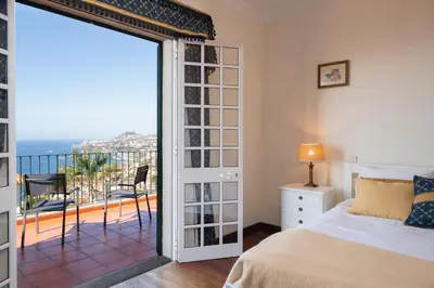 a bedroom with a bed and a view of the ocean at OurMadeira - Villa Vista Sol in Funchal