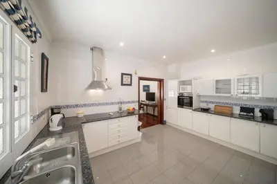 a large kitchen with white cabinets and a sink at OurMadeira - Villa Vista Sol in Funchal