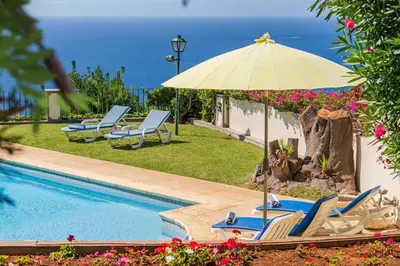 a pool with chairs and an umbrella and the ocean at OurMadeira - Villa Vista Sol in Funchal