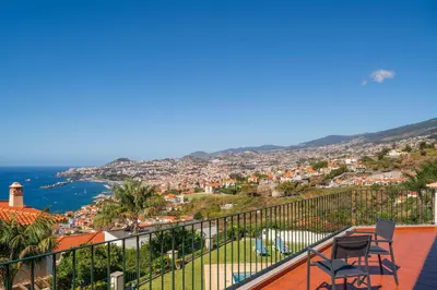 a balcony with two chairs and a view of the ocean at OurMadeira - Villa Vista Sol in Funchal