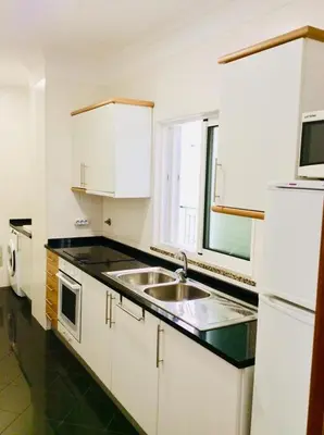 a white kitchen with a sink and a microwave at Canico Penthouse with Sea View in Caniço