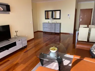 a living room with a television and a glass table at Canico Penthouse with Sea View in Caniço