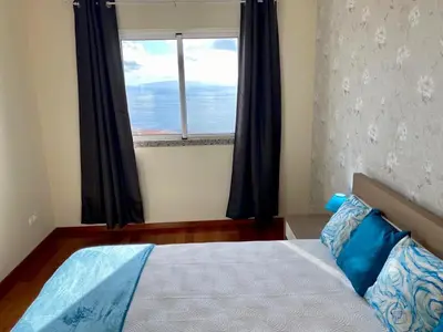 a bedroom with a bed with a large window at Canico Penthouse with Sea View in Caniço