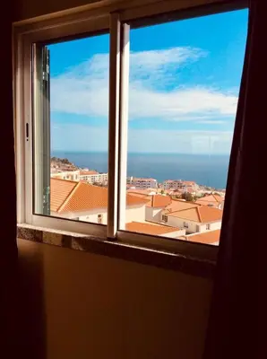 an open window with a view of a city at Canico Penthouse with Sea View in Caniço
