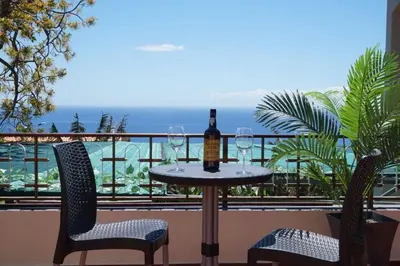 a table with two glasses of wine on a balcony at Tabua Village Madeira Suite VIP in Ribeira Brava
