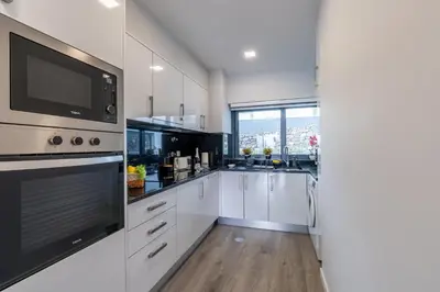 a kitchen with white cabinets and a large window at Sea View Balcony by Homie in Santa Cruz