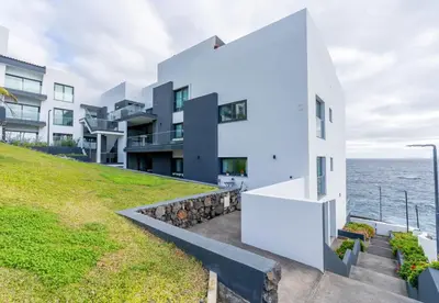a white house with the ocean in the background at Sea View Balcony by Homie in Santa Cruz
