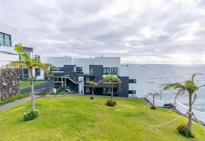 a building with palm trees in front of the ocean at Sea View Balcony by Homie in Santa Cruz