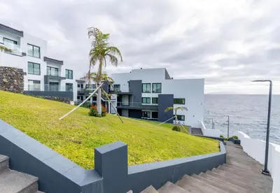 a building with a grassy hill next to the ocean at Sea View Balcony by Homie in Santa Cruz