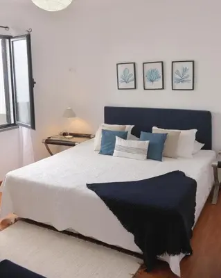 a bedroom with a large white bed with blue pillows at Casa Azul - Ocean View in Porto Moniz